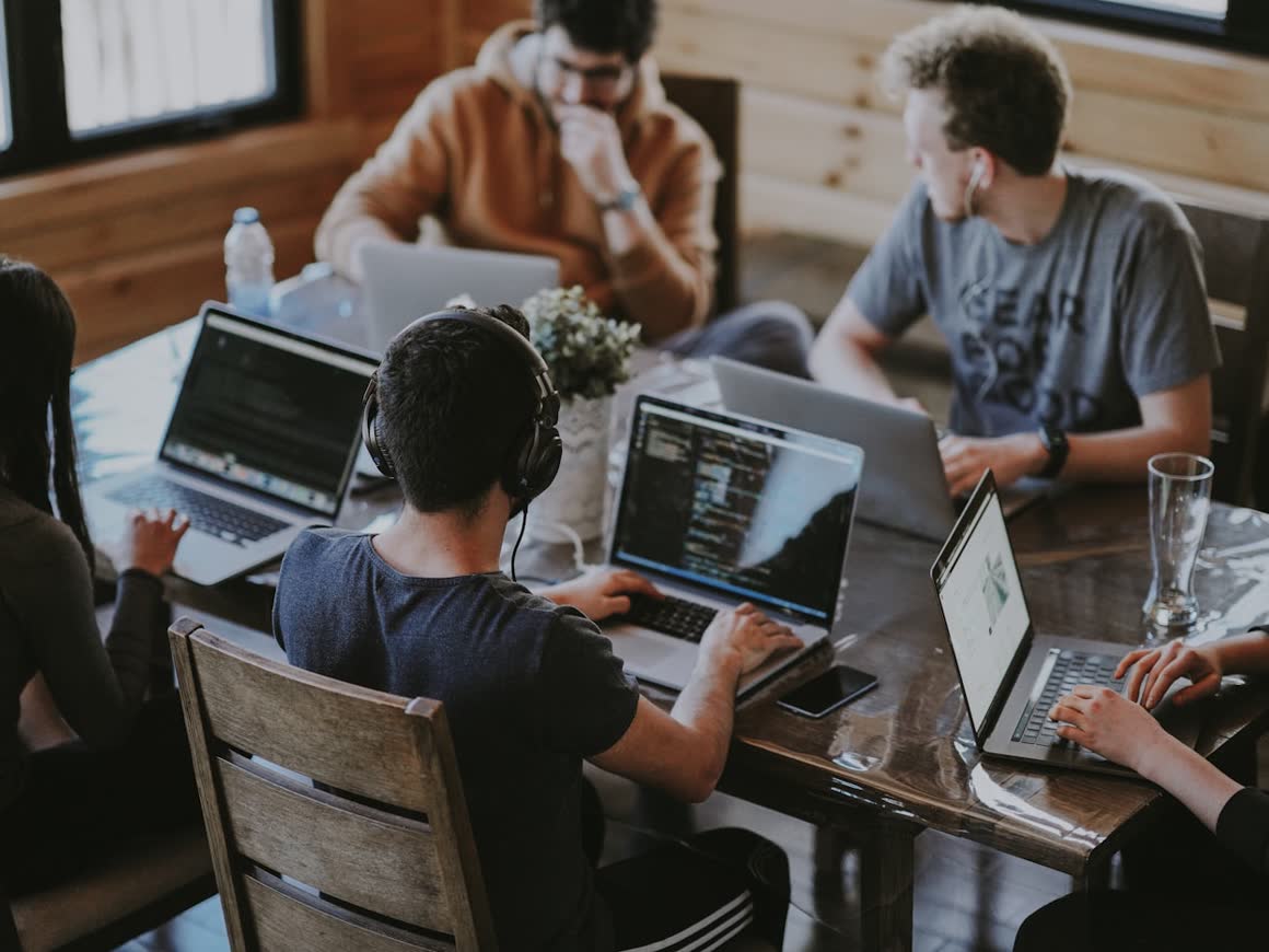 A team of engineers working together on laptops around a shared table